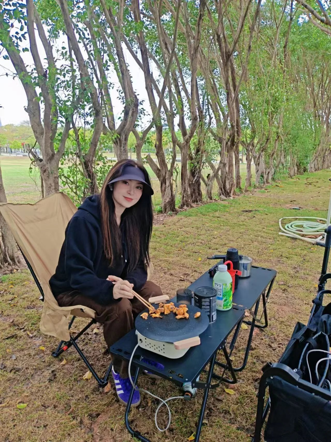 Woman seated outdoors beside camping gear