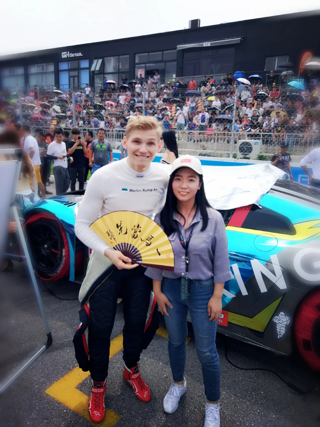 Two people posing beside a race car