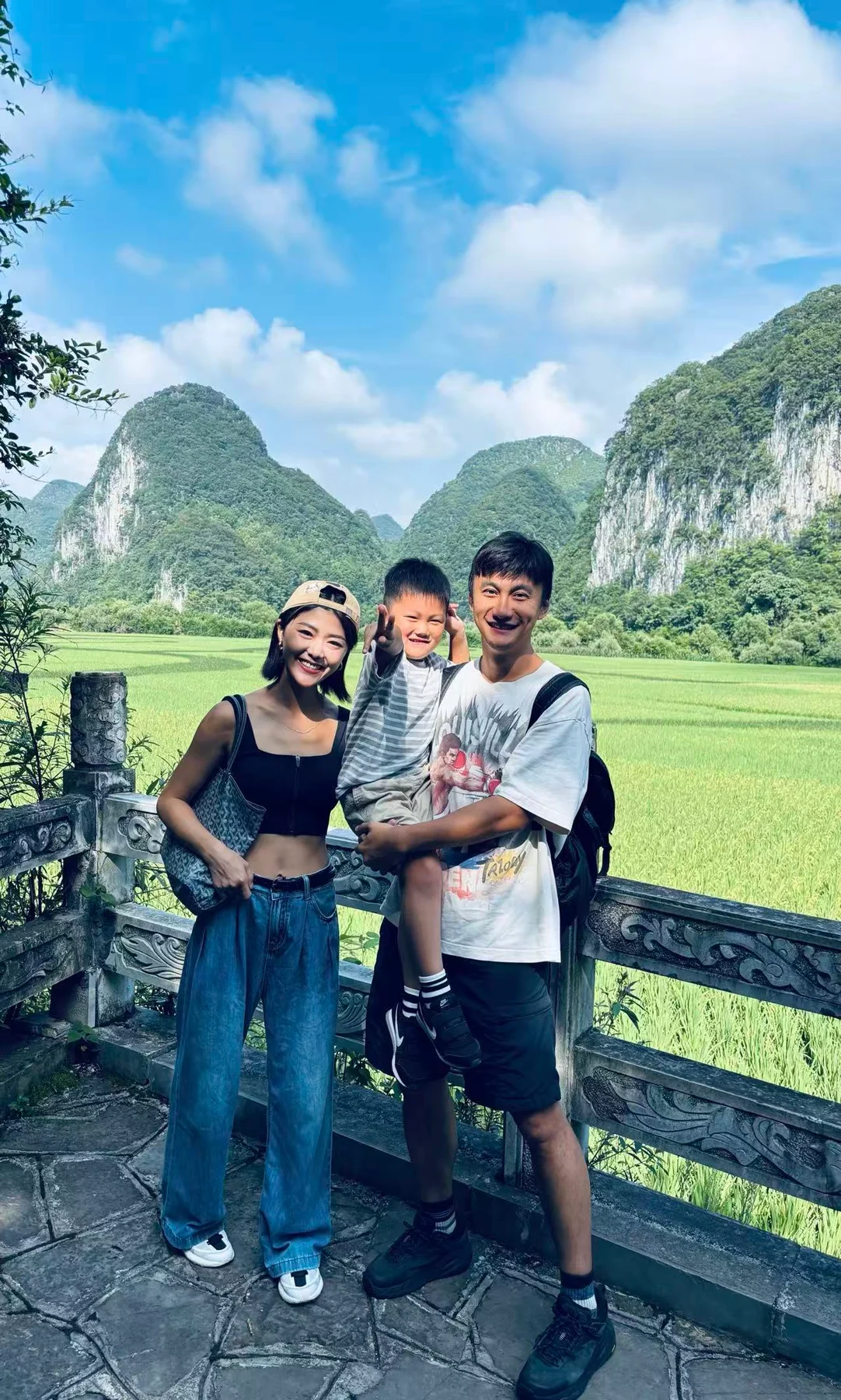 Three people together with green mountains behind them